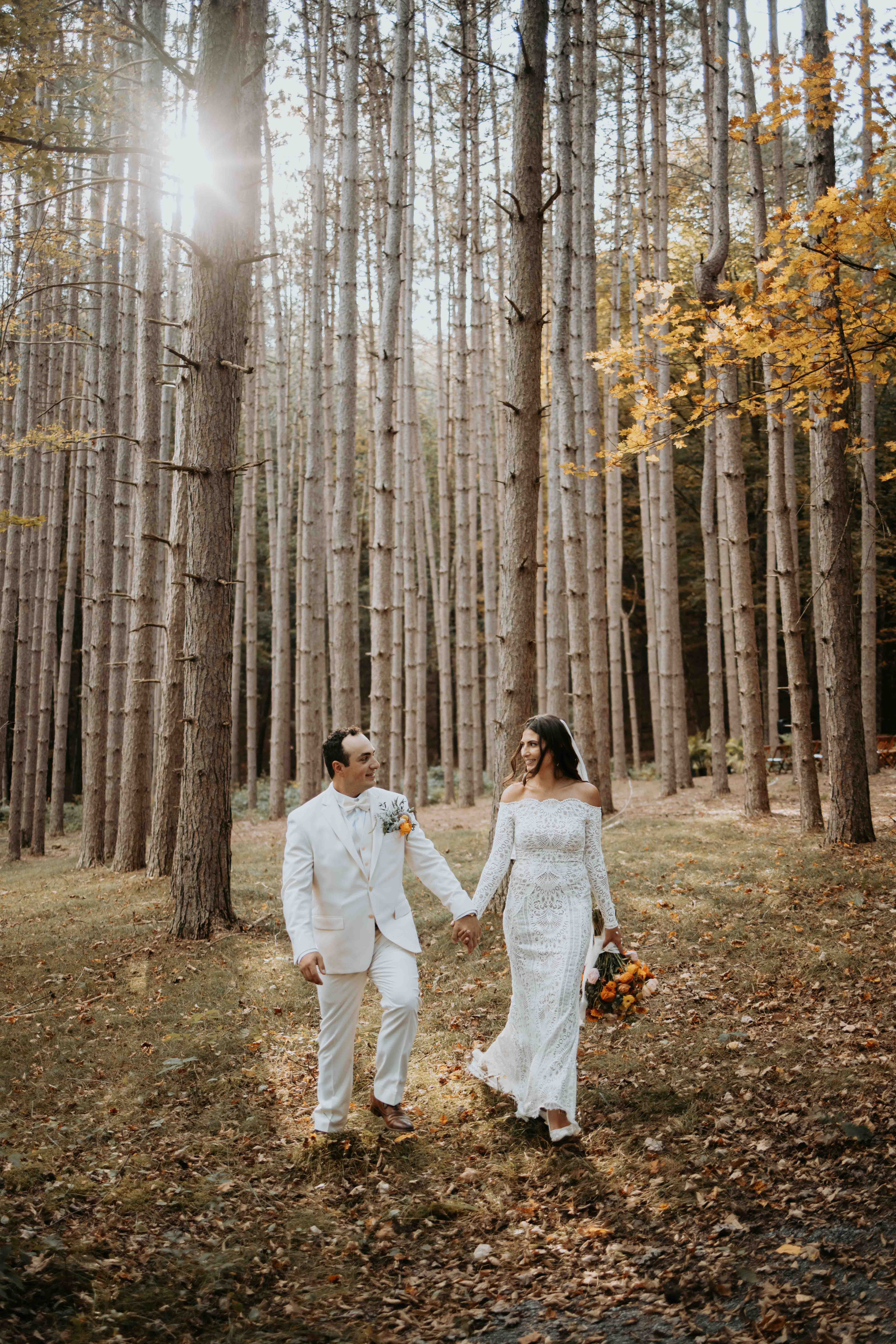 Couple walking through the tall pine grove at The Roxbury Barn